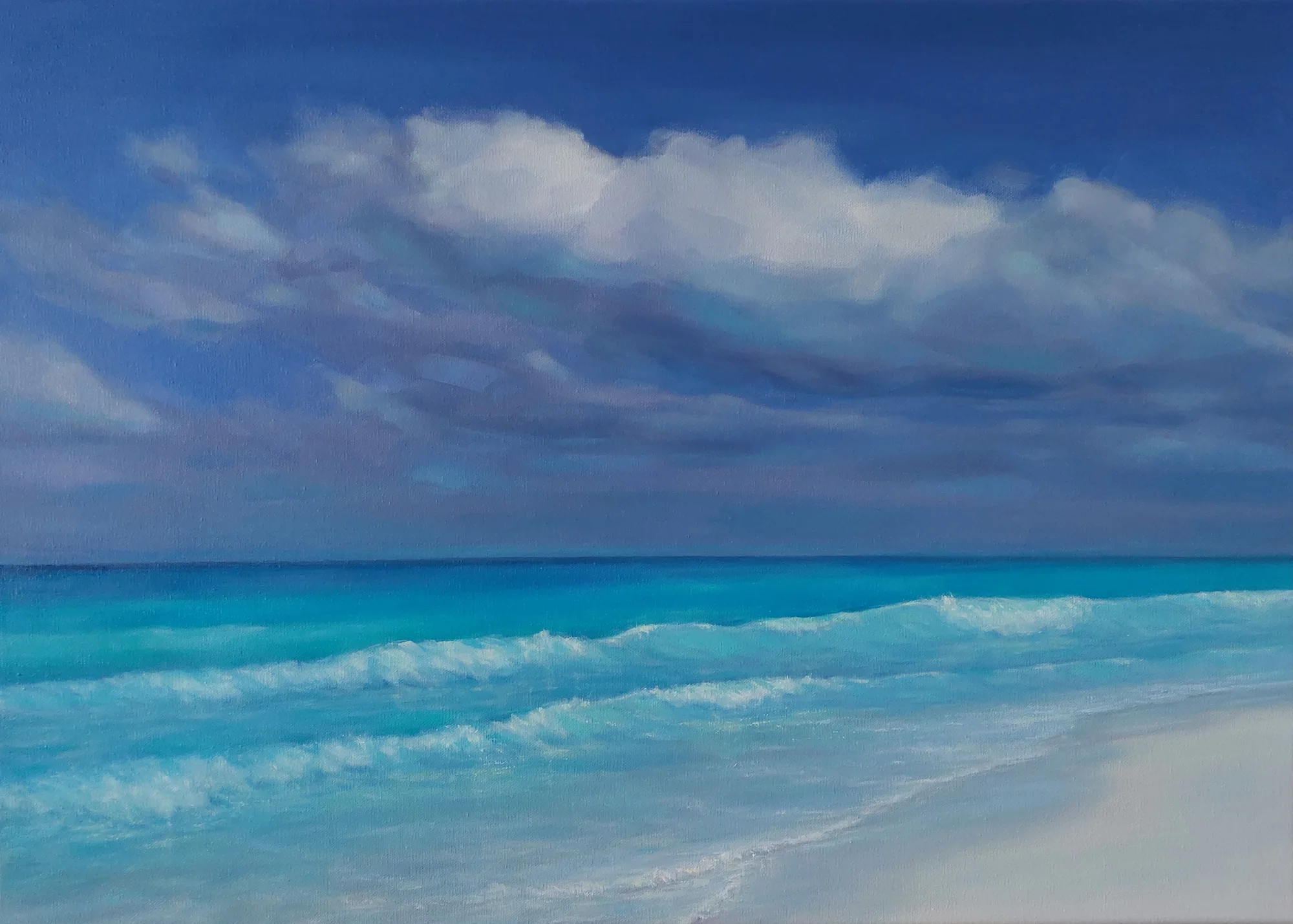 Billowing clouds above rolling surf and a pale beach